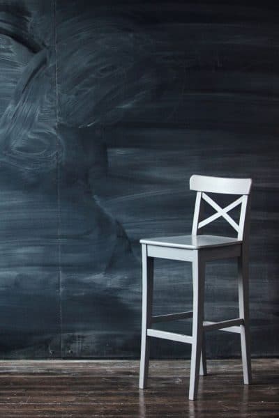 A chair in front of a blackboard.