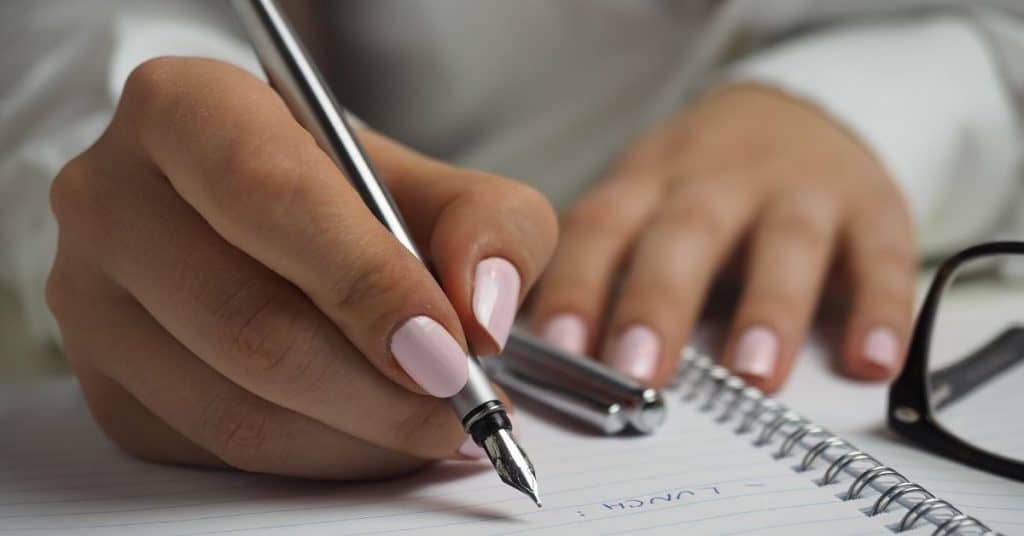 A teacher's hand writing a to do list.