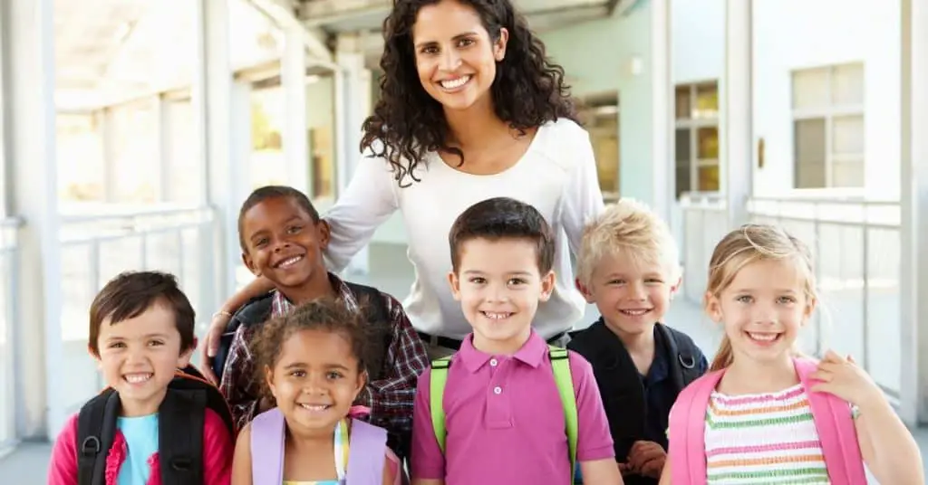 Smiling female teacher surrounded by students.