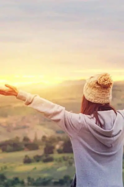 A woman with her arms outstretched looking at the sunrise.