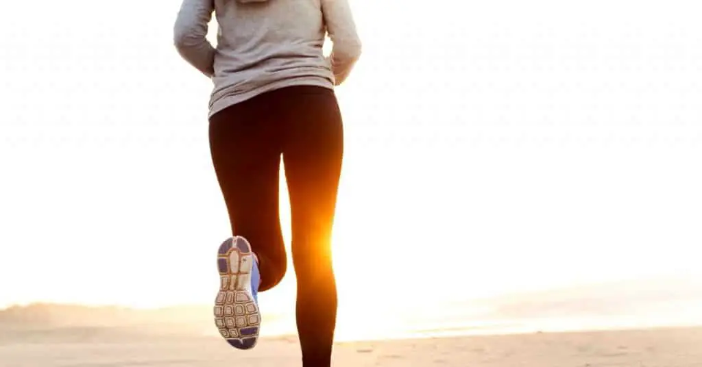 Woman running on the beach as one of her ways to teacher wellness.