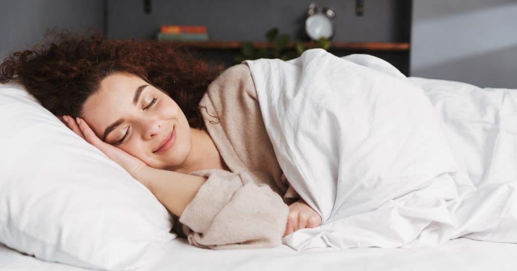 Woman snuggled up in bed sleeping.