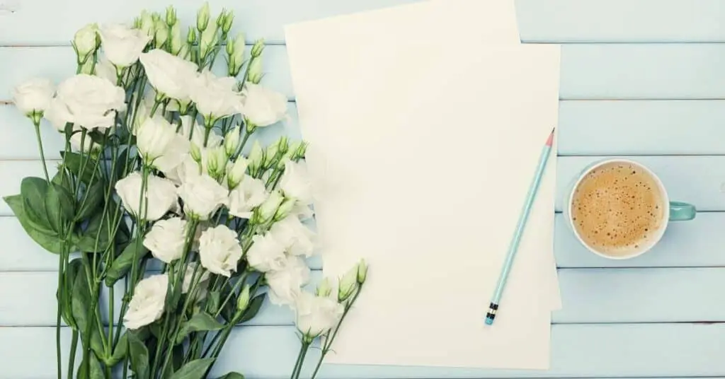 Paper, pencil, coffee and flowers on a blue background.