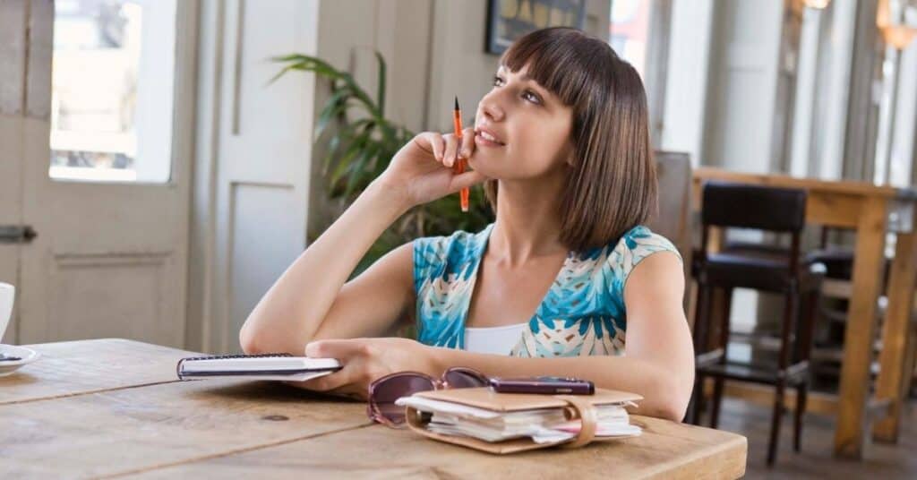 Woman looking up as she ponders what to write on her stop doing list.