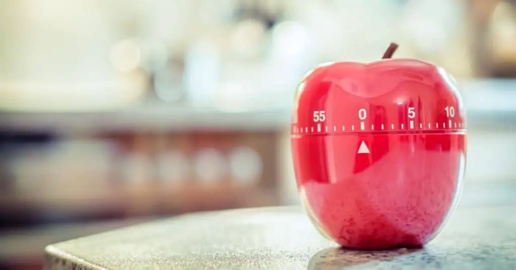 An apple timer on a desk.