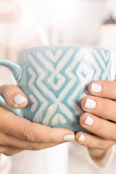 A woman's hand holding a blue cup.
