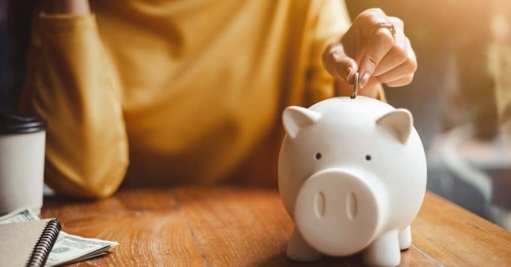 Woman putting money into a piggy bank.