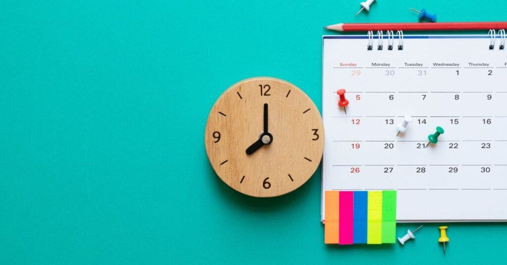 A calendar, clock and post its on a vibrant aqua background