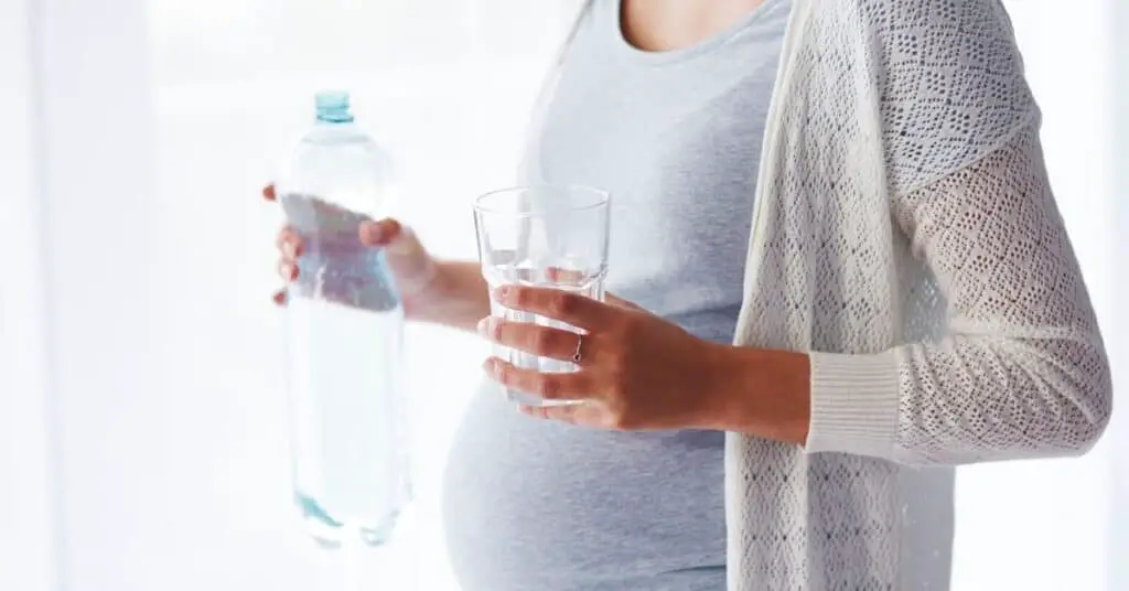 Pregnant teacher having bottle of water.