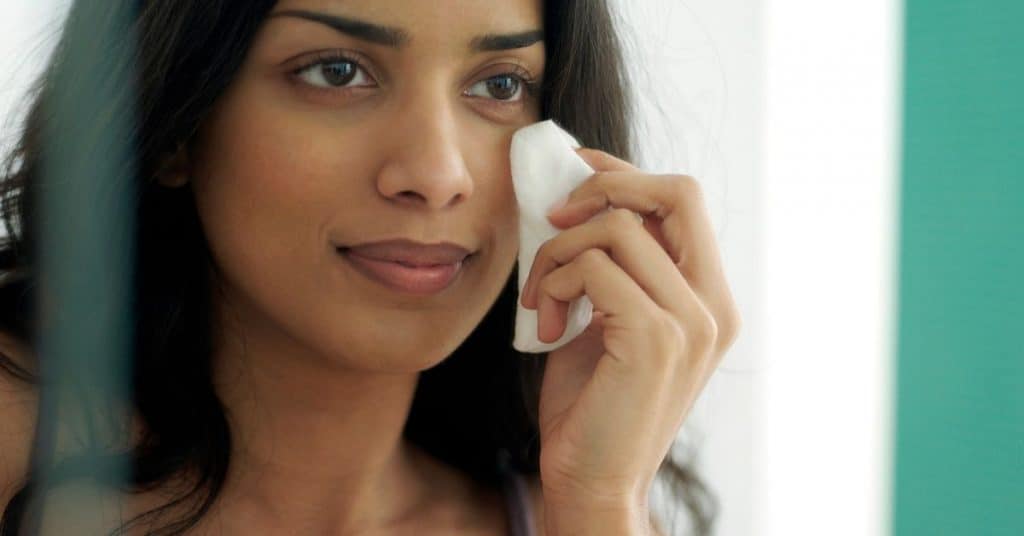 woman taking off her makeup as part of her bedtime routine