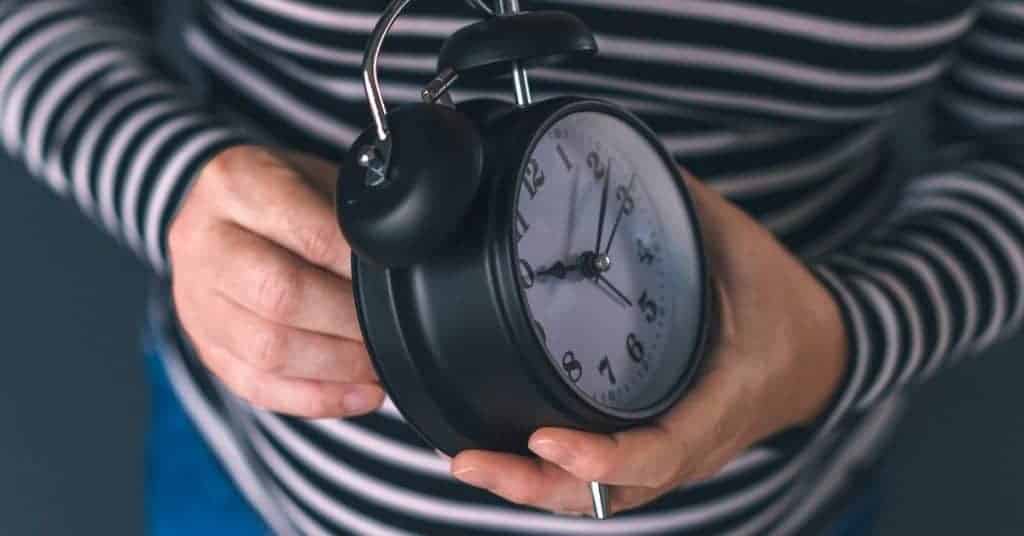 woman setting a bedtime alarm on her clock