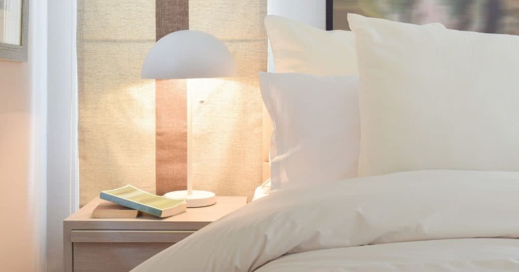 bed with bedside lamp on as part of tips to sleep better